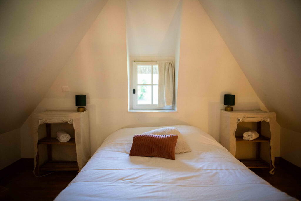 Chambre cosy avec lit double, tables de nuit et fenêtre, dans la Chaumière Les Peupliers en Normandie.