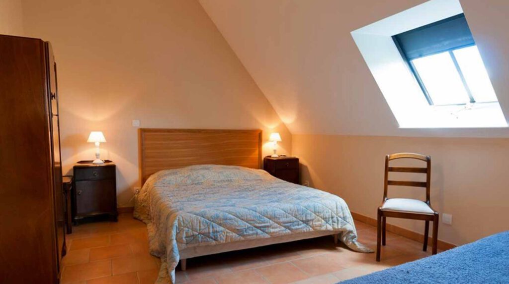 Chambre confortablement aménagée avec lit double, éclairage doux et fenêtre donnant sur l'extérieur.