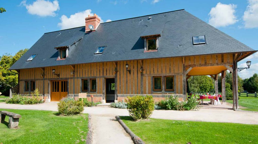 Maison de la Mare, gîte normand en colombages, idéale pour mariages et séminaires, entourée de verdure.