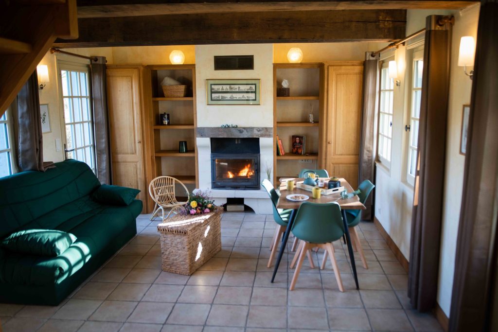 Intérieur accueillant de la Chaumière Les Peupliers, avec salon, cheminée et salle à manger, lumineux et décoré avec goût.