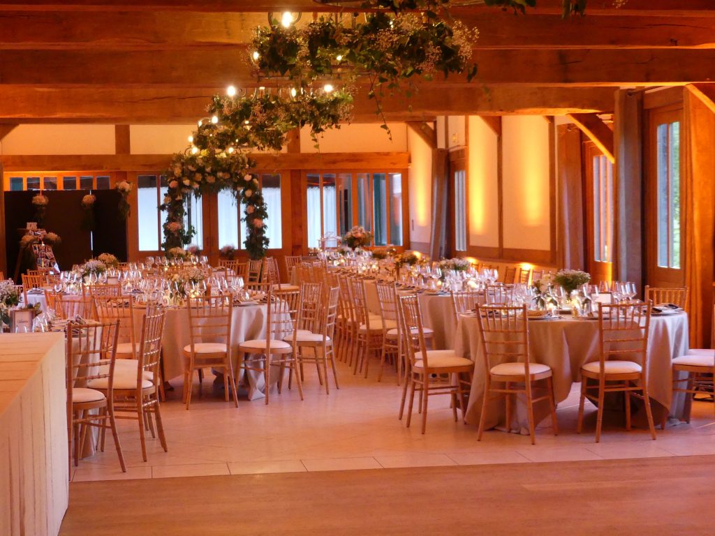 Salle de réception élégante en Normandie, décorée pour un mariage, avec tables dressées et éclairage chaleureux.
