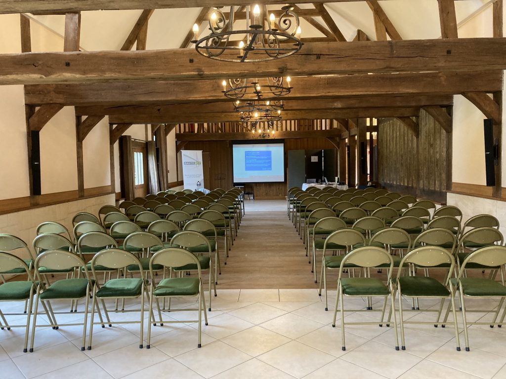 Salle de séminaire en Normandie avec chaises disposées, murs en bois et écran de projection. Idéale pour événements professionnels.